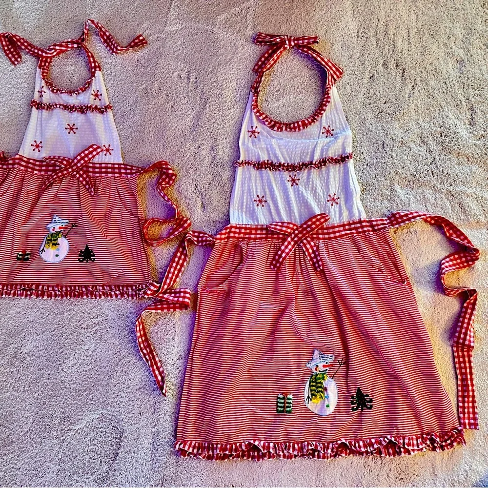 Mother and daughter matching Christmas aprons with pockets in each one.